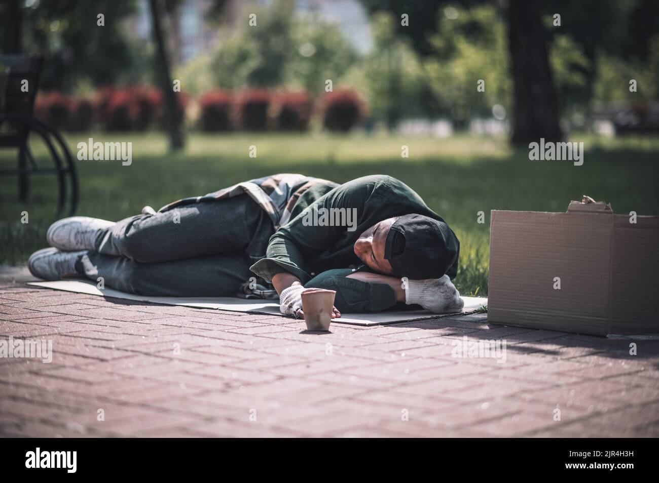 Uomo dalla pelle scura che dorme a terra nel parco Foto Stock
