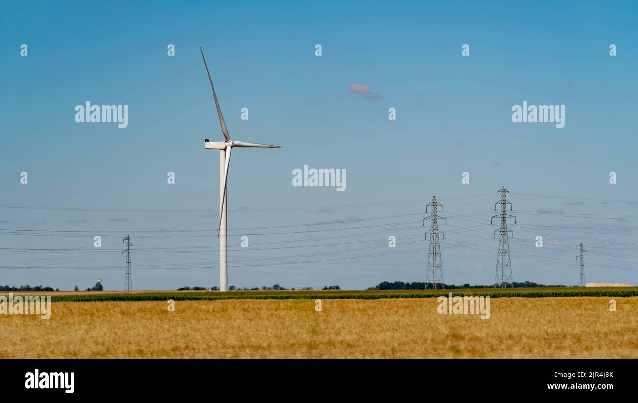 Linee elettriche ad alta tensione che trasportano energia rinnovabile da una turbina eolica Foto Stock