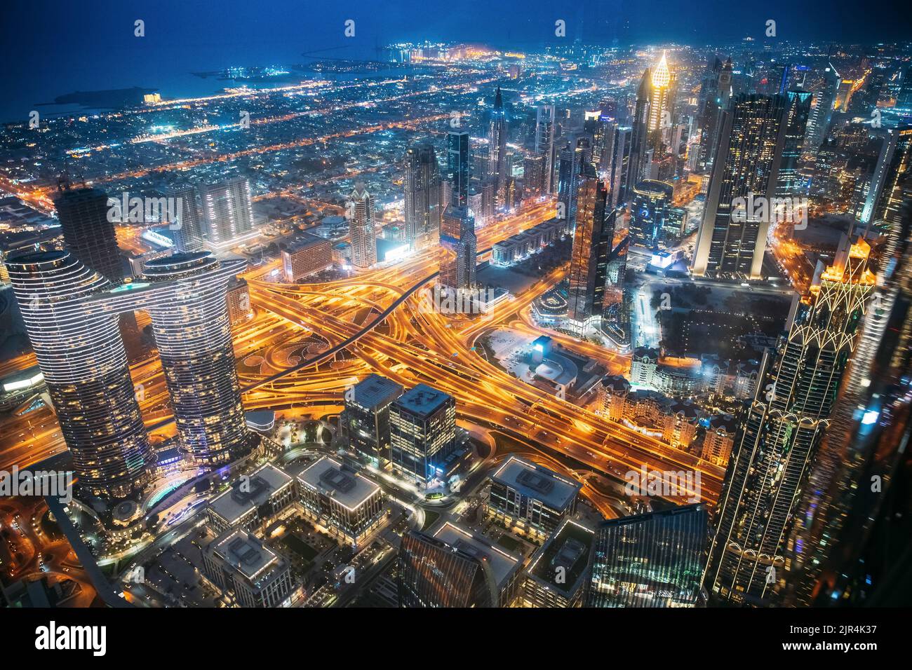 Sfondo della città illuminato con grattacieli e architettura urbana moderna nella città turistica di Dubai. Traffico notturno di strada nello skyline di Dudai Foto Stock