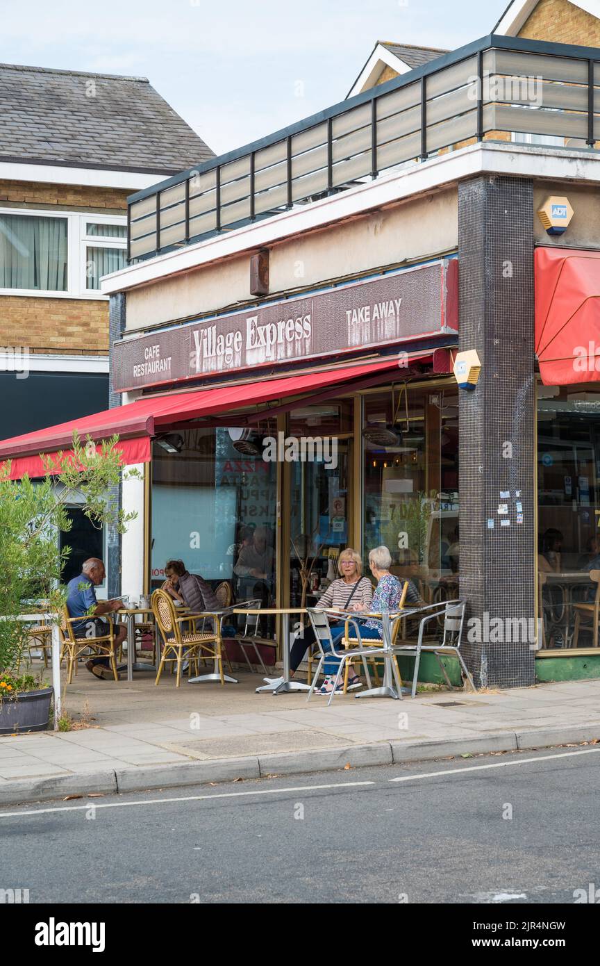 Le persone sedute all'interno e ai tavoli sul marciapiede possono gustare cibo e bevande al ristorante Village Express su Clive Parade, Northwood, Middlesex, Inghilterra, Regno Unito Foto Stock