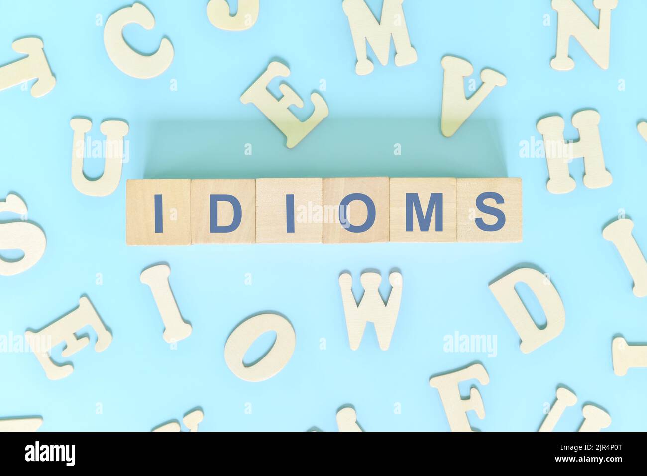 Idiomi o idioma concetto nella lezione di grammatica inglese. Blocchi di legno tipografia piatta giacitura su sfondo blu. Foto Stock
