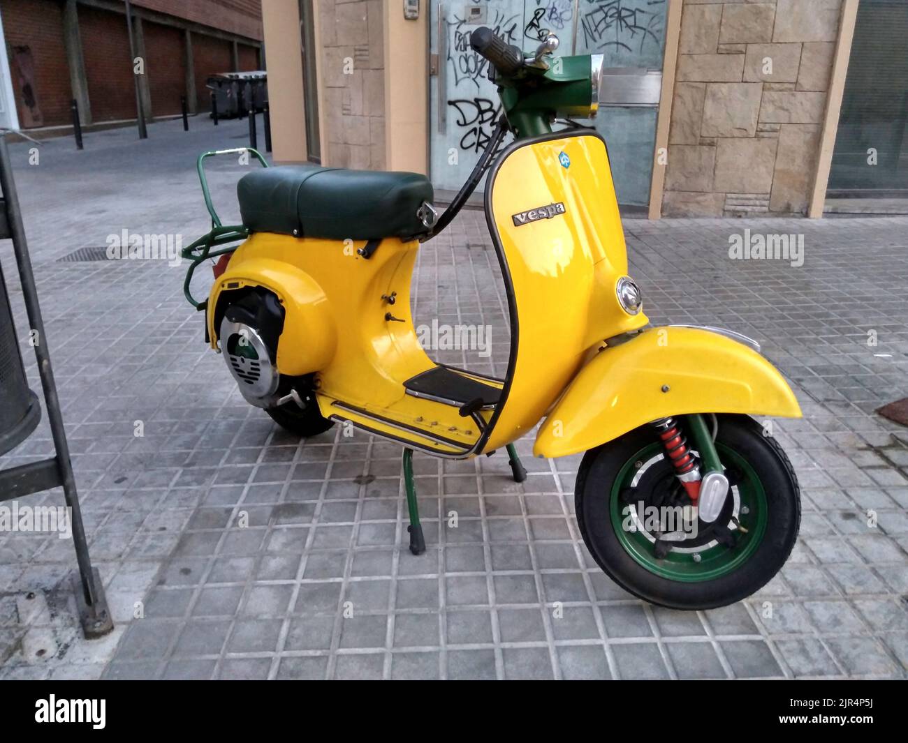 Un primo piano di un classico scooter Piaggio Vespa giallo sulla strada Foto Stock