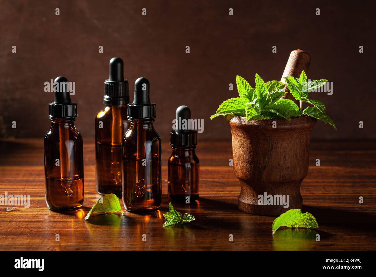 Menta fresca foglie di menta piperita nel mortaio e olio essenziale in bottiglie contagocce Foto Stock
