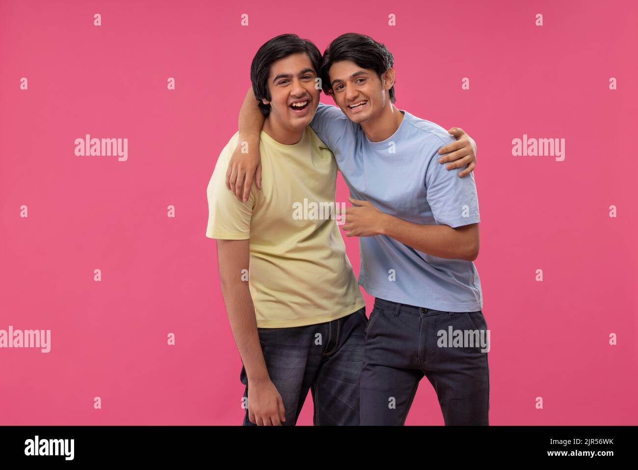 Due amici felici che abbracciano lo sfondo rosa Foto Stock