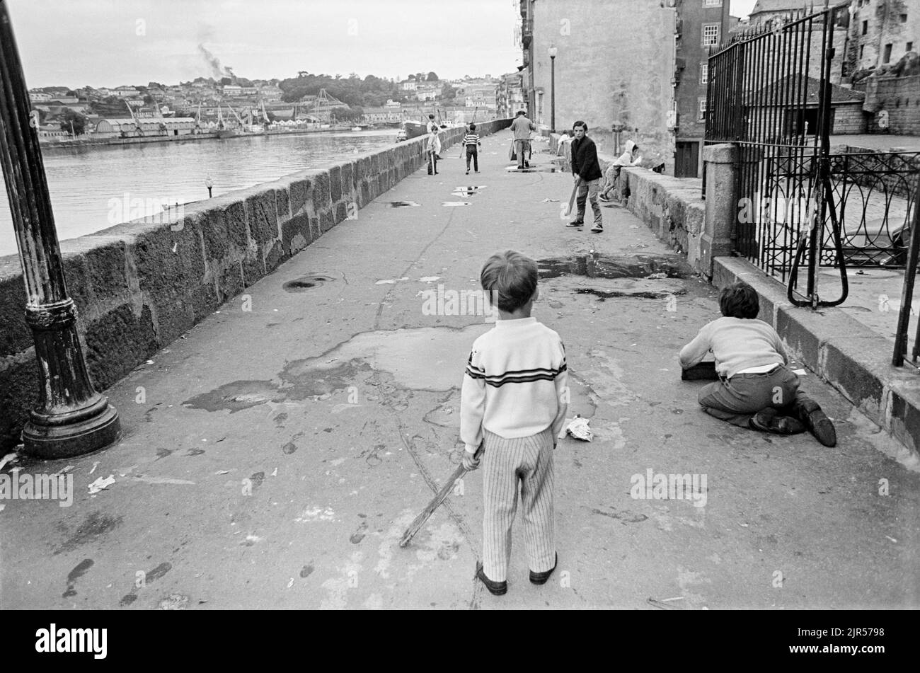 PORTOGALLO - PORTO - 1970. I bambini giocano a pipistrello e palla sul lungomare Cais da Estiva del fiume Douro nel quartiere Ribeira di Porto, nel Nord Foto Stock