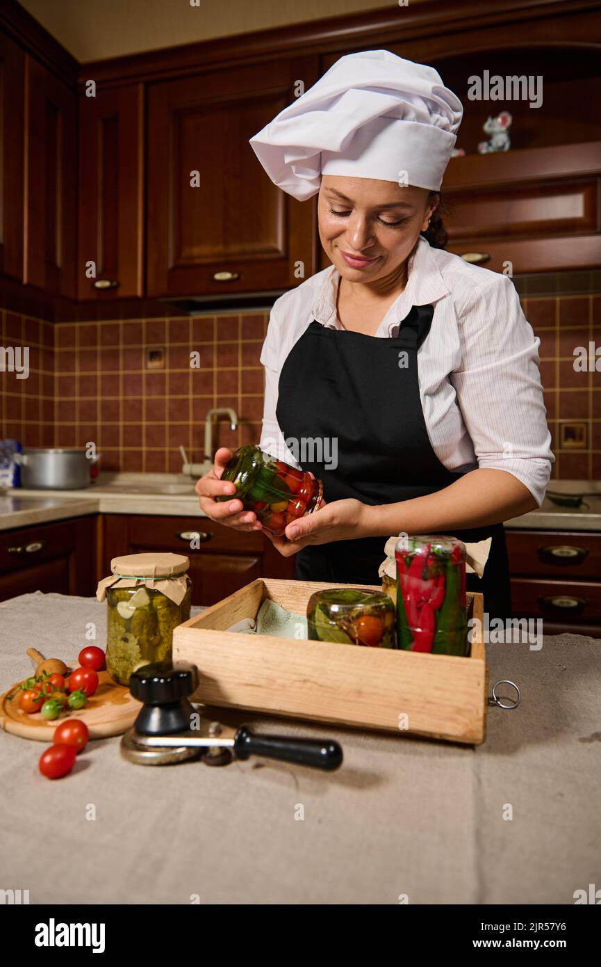 Carina donna stucco vasi con conserve fatte in casa fermentate e verdure marinate in una cassa di legno. Inscatolamento. Decapaggio Foto Stock