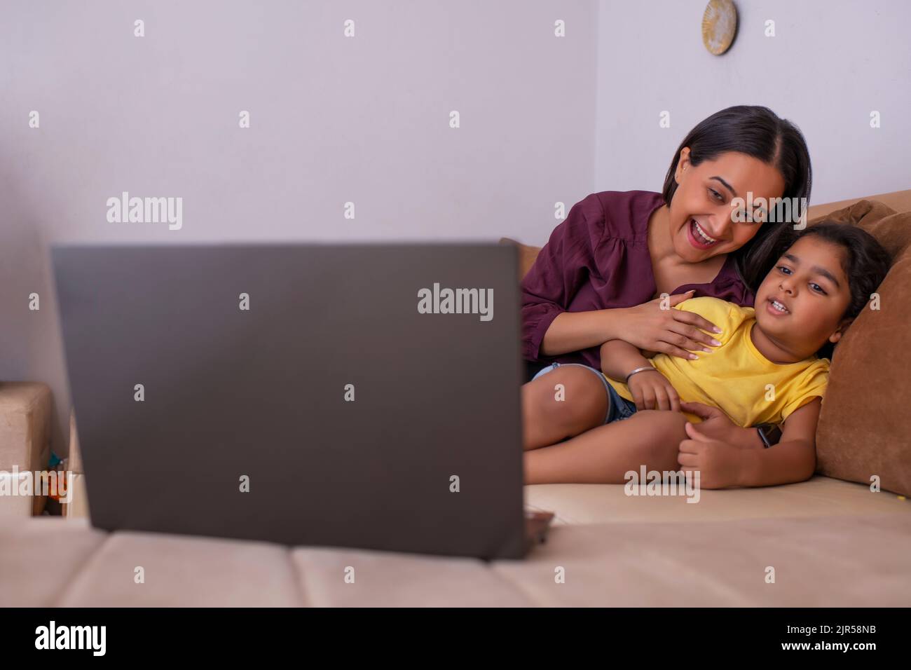 Madre e figlia che guardano i cartoni animati sul laptop nel soggiorno Foto Stock