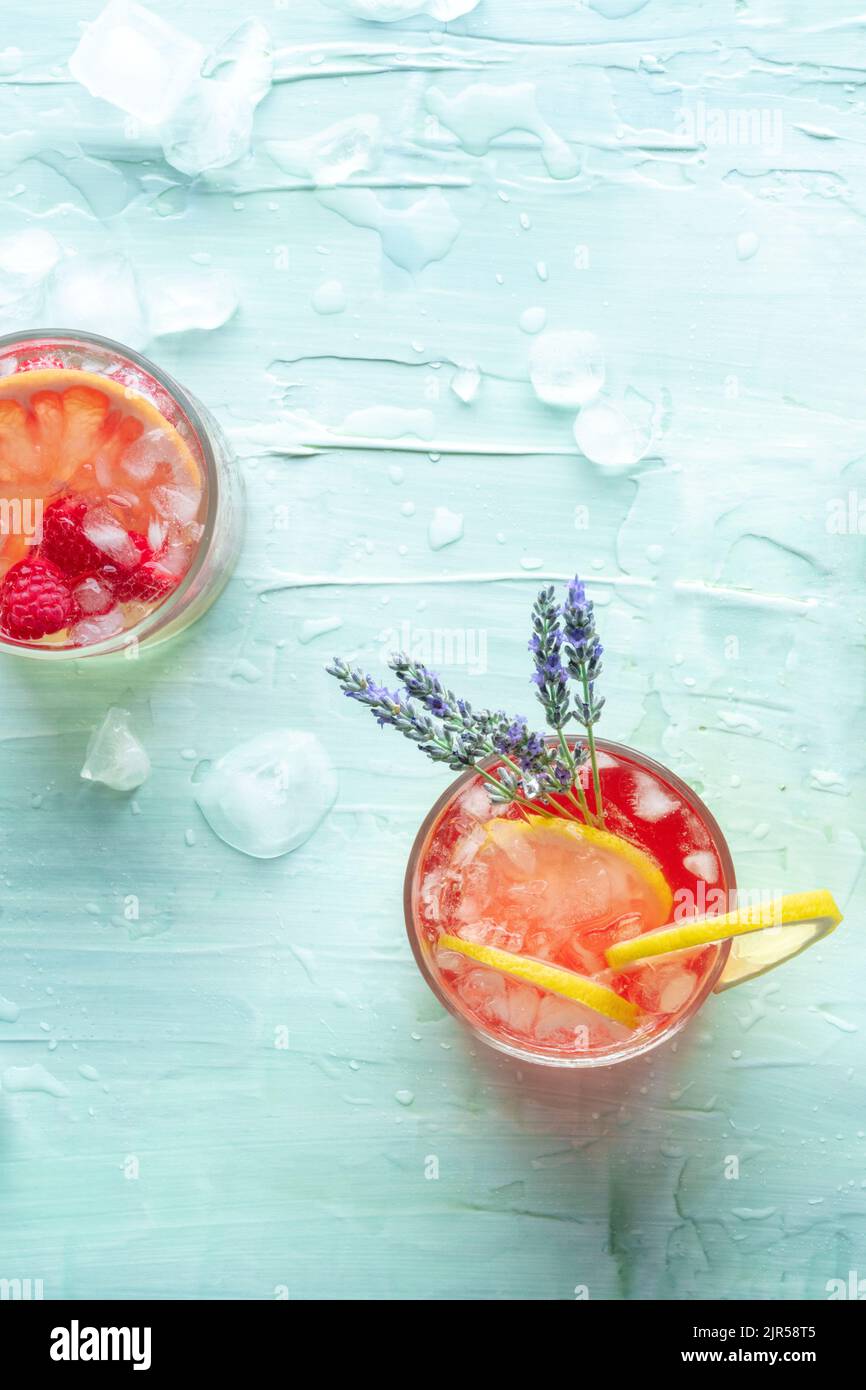 Cocktail o mocktail estivi freschi, bevande fredde con agrumi e lavanda, limonata da festa, shot dall'alto su sfondo blu con ghiaccio Foto Stock