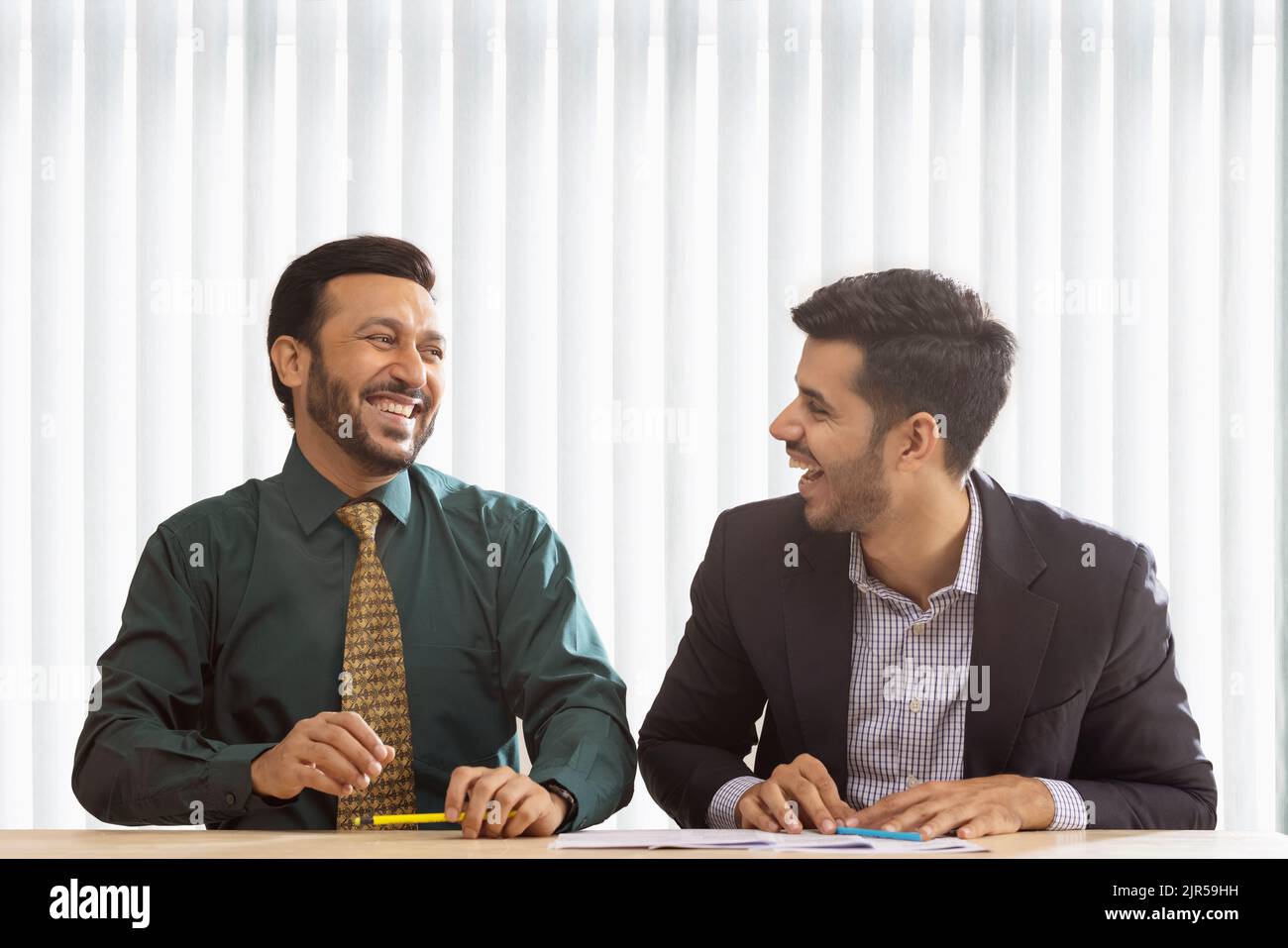 Colleghi aziendali che parlano e ridono mentre si siedono insieme. Foto Stock
