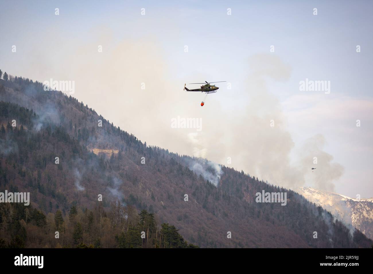 Elicottero con secchio d'acqua pronto per spegnere l'area dei fuochi d'acqua in montagna Foto Stock