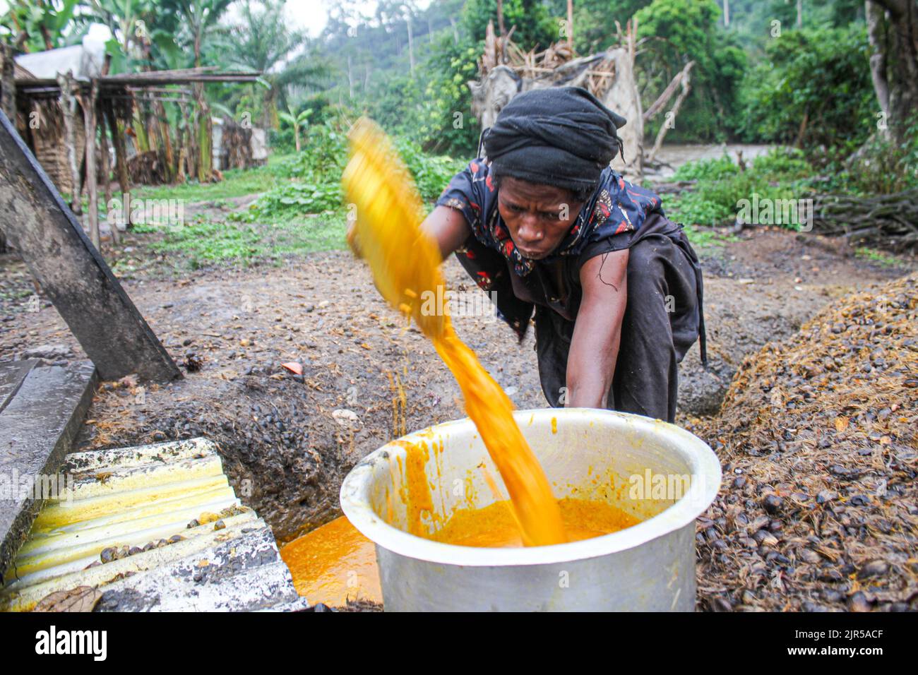 Produzione artigianale di olio di palma chiamato 'Seketa' (Stir) nella lingua locale da parte di donne del villaggio di Mpety a Walikale, Kivu Nord (RDC orientale), 15 dicembre 2021. Fabrication artisanale de l’huile de palme appelee en language locale “Seketa“ (Remuer) par des femmes du village Mpety a Walikale au Nord Kivu (Est de la RD Congo), le 15 dicembre 2021. Foto Stock