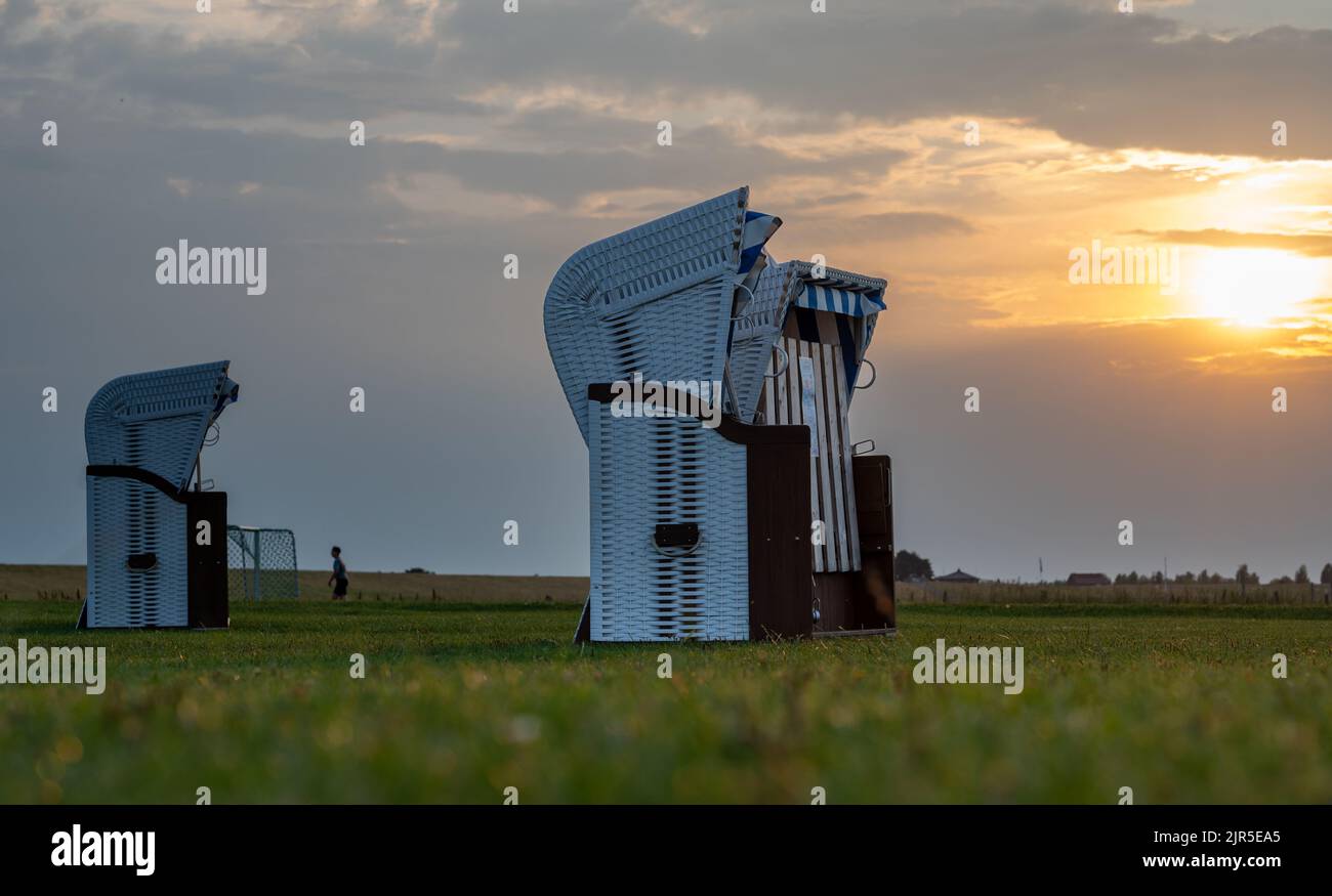 Tre sedie a sdraio durante il tramonto ad Altenbruch vicino a Cuxhaven, Germania. Foto Stock