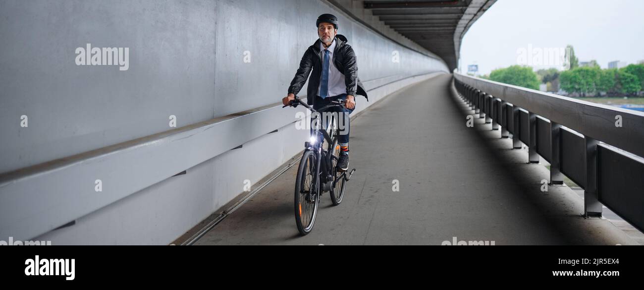 Uomo d'affari che viaggia per lavoro, in bicicletta sul ponte, concetto di stile di vita sostenibile. Foto Stock