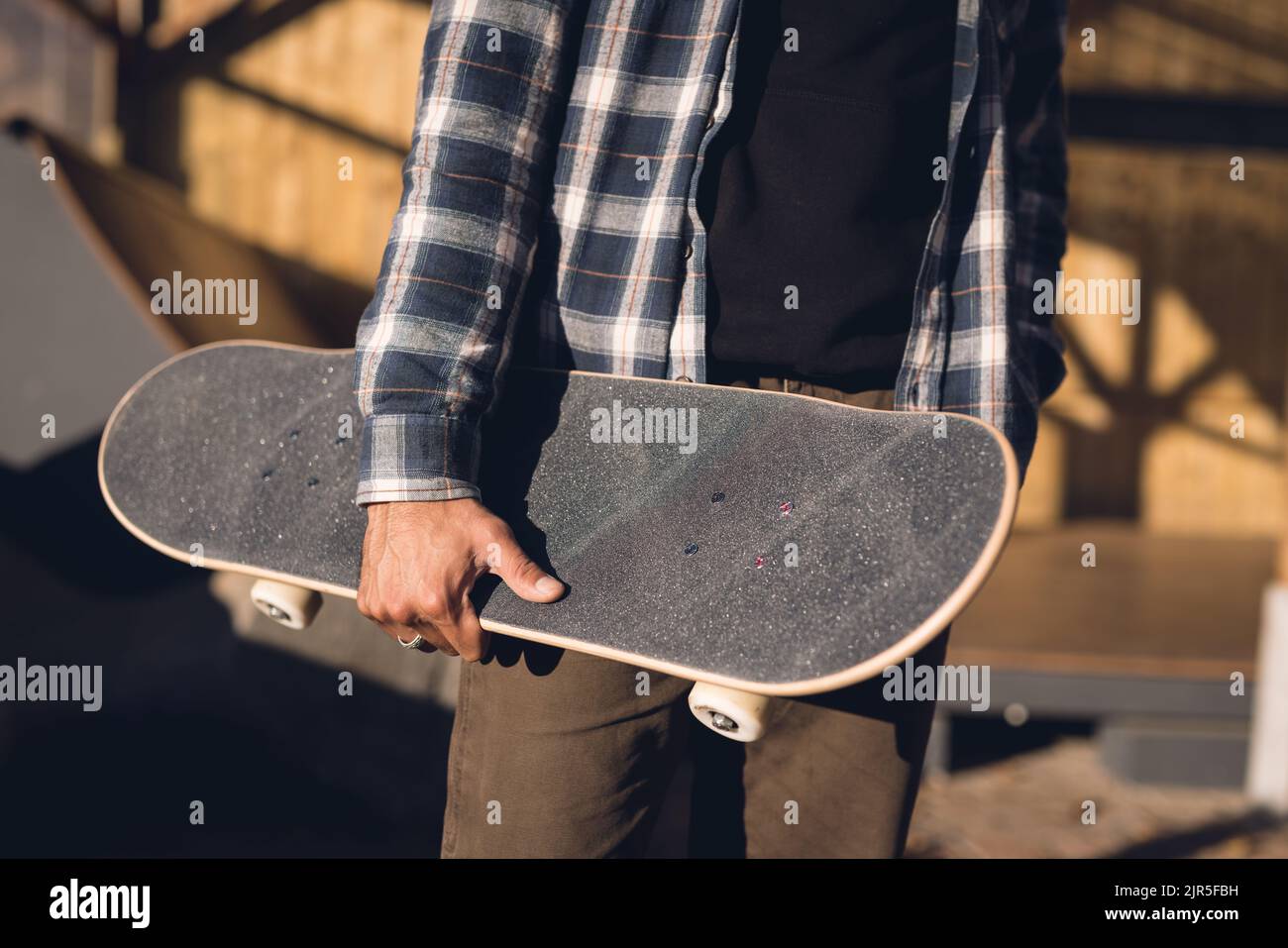 Immagine della sezione centrale di un uomo ispanico con skateboard in skate Park Foto Stock