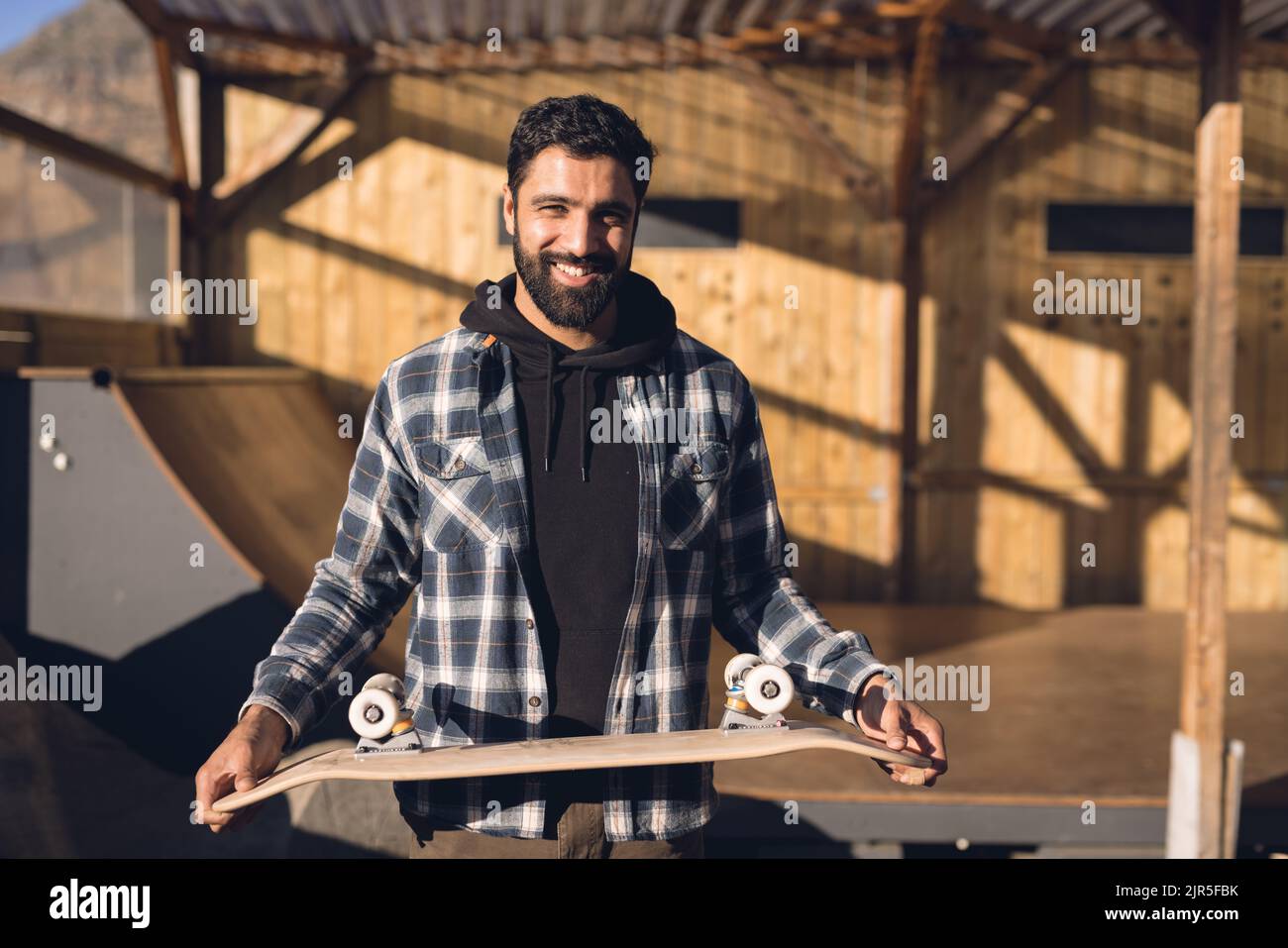Immagine di Happy hispanic uomo con skateboard in skate Park Foto Stock
