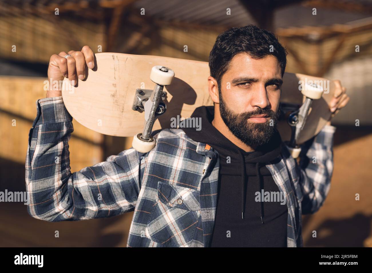 Immagine di un serio uomo ispanico con skateboard in skate Park Foto Stock