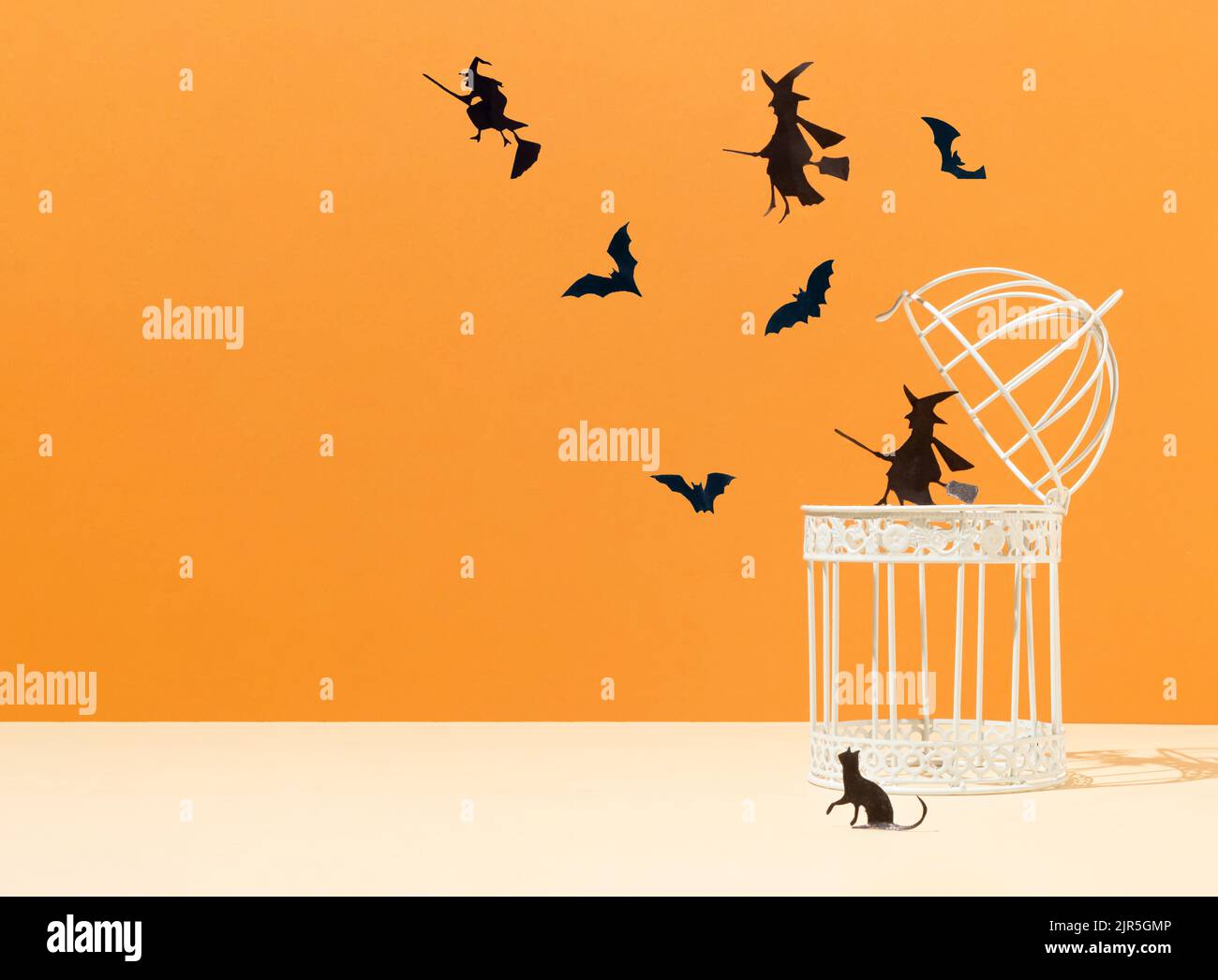 Concetto minimal creativo con gabbia per uccelli, silhouette di pipistrelli e streghe su sfondo arancione. Concetto spaventoso di Halloween con lo spazio della copia. Estetica moderna. Foto Stock Concetto minimal creativo con gabbia per uccelli, silhouette di pipistrelli e streghe su sfondo arancione. Concetto spaventoso di Halloween con lo spazio della copia. Estetica moderna. Foto Stock
