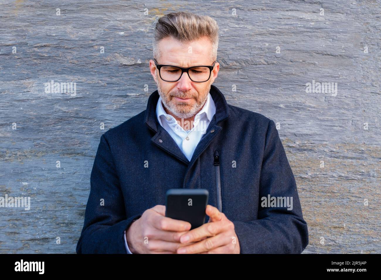 Ritratto dell'uomo d'affari negli occhiali che lavorano sullo smartphone Foto Stock