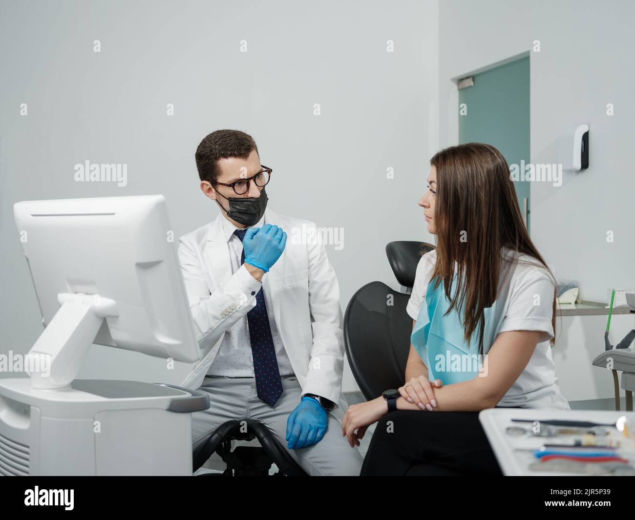 Ortodontista maschile con paziente femminile che guarda su uno schermo durante una consultazione medica presso la dentistica Foto Stock