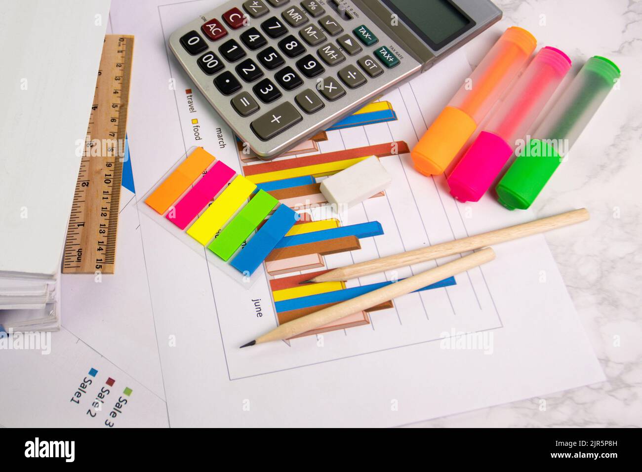 documentare il foglio grafico a colori per la presentazione sul tavolo della sala in ufficio con la calcolatrice dell'attrezzatura, la matita, la penna a colori evidenziata Foto Stock