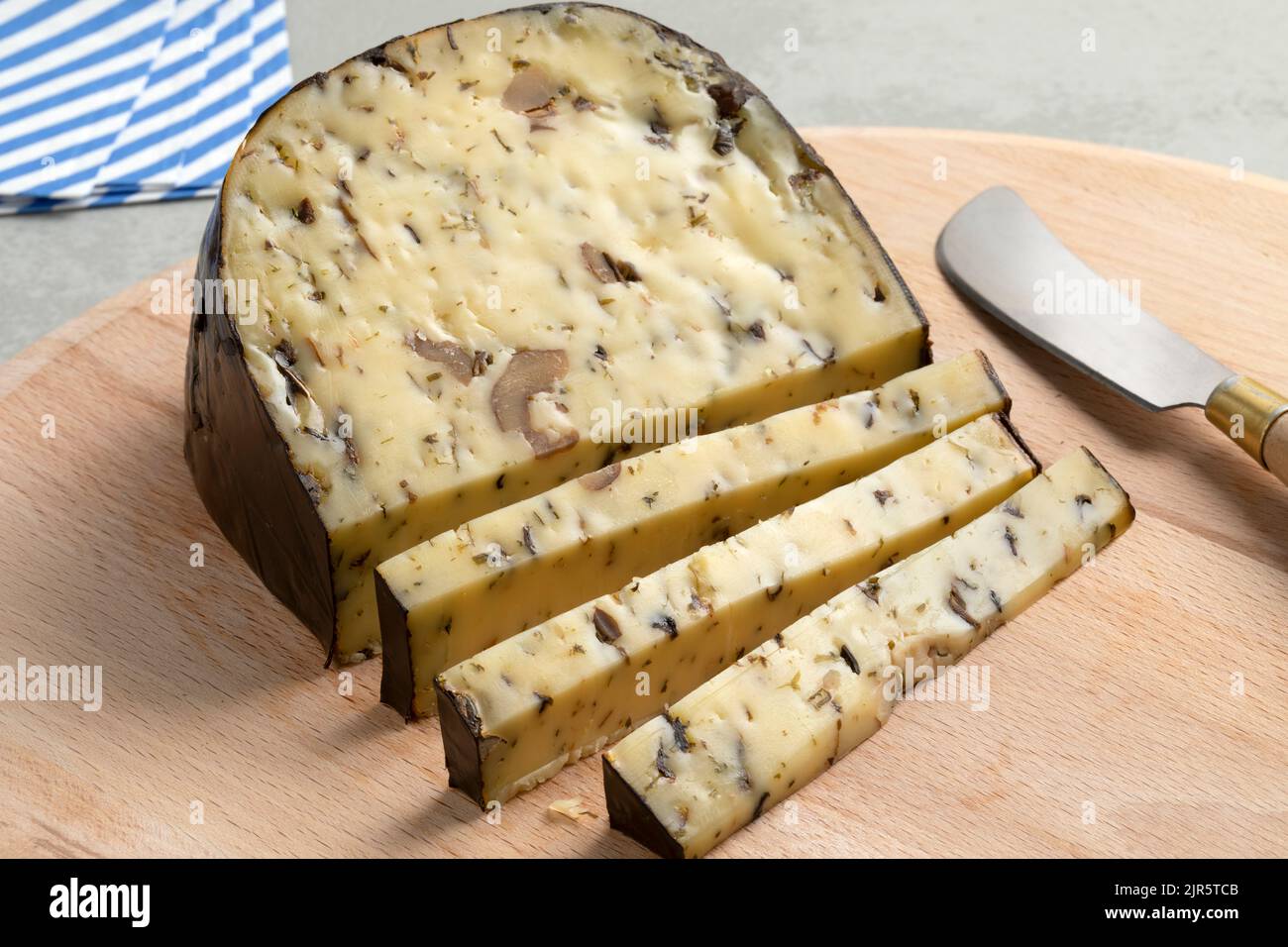 Pezzo di formaggio Gouda con funghi selvatici su un tagliere da vicino Foto Stock