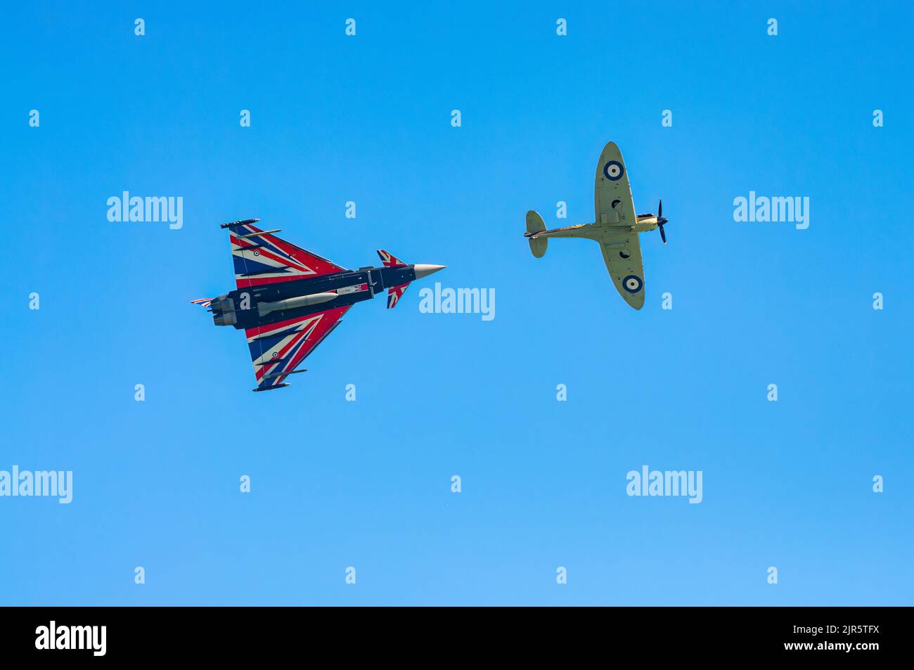 Uno Spitfire della seconda Guerra Mondiale e un moderno jet fighter Typhoon volano davanti all'annuale Eastbourne Airshow, uno dei più grandi eventi liberi del suo genere Foto Stock
