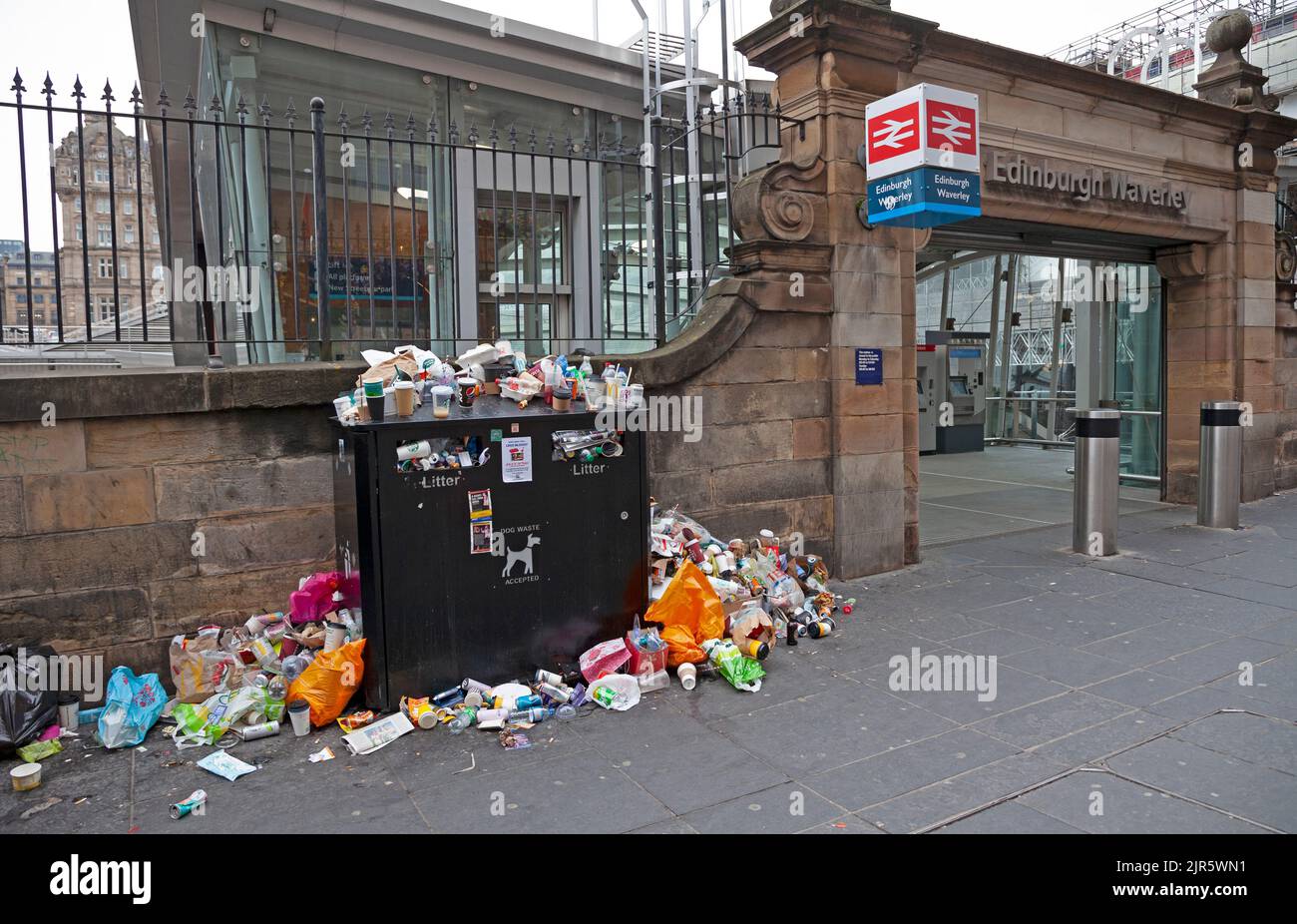 Stazione di Waverley, Edimburgo, Scozia, Regno Unito. 22nd agosto 2022. È stato un peccato per arrivare in vacanza e per essere accolto da un clima noioso e arido, anche se la temperatura è di 17 gradi centigradi, ma peggio ancora sono i bidoni dei rifiuti sui marciapiedi ammassati in alto e traboccanti di rifiuti scartati subito fuori dall'entrata della stazione ferroviaria. Ciò è dovuto al fatto che gli operatori della pulizia del Consiglio della città di Edimburgo sono il quinto giorno di undici giorni di sciopero sulla retribuzione. Credit: Arch White/alamy live news. Foto Stock