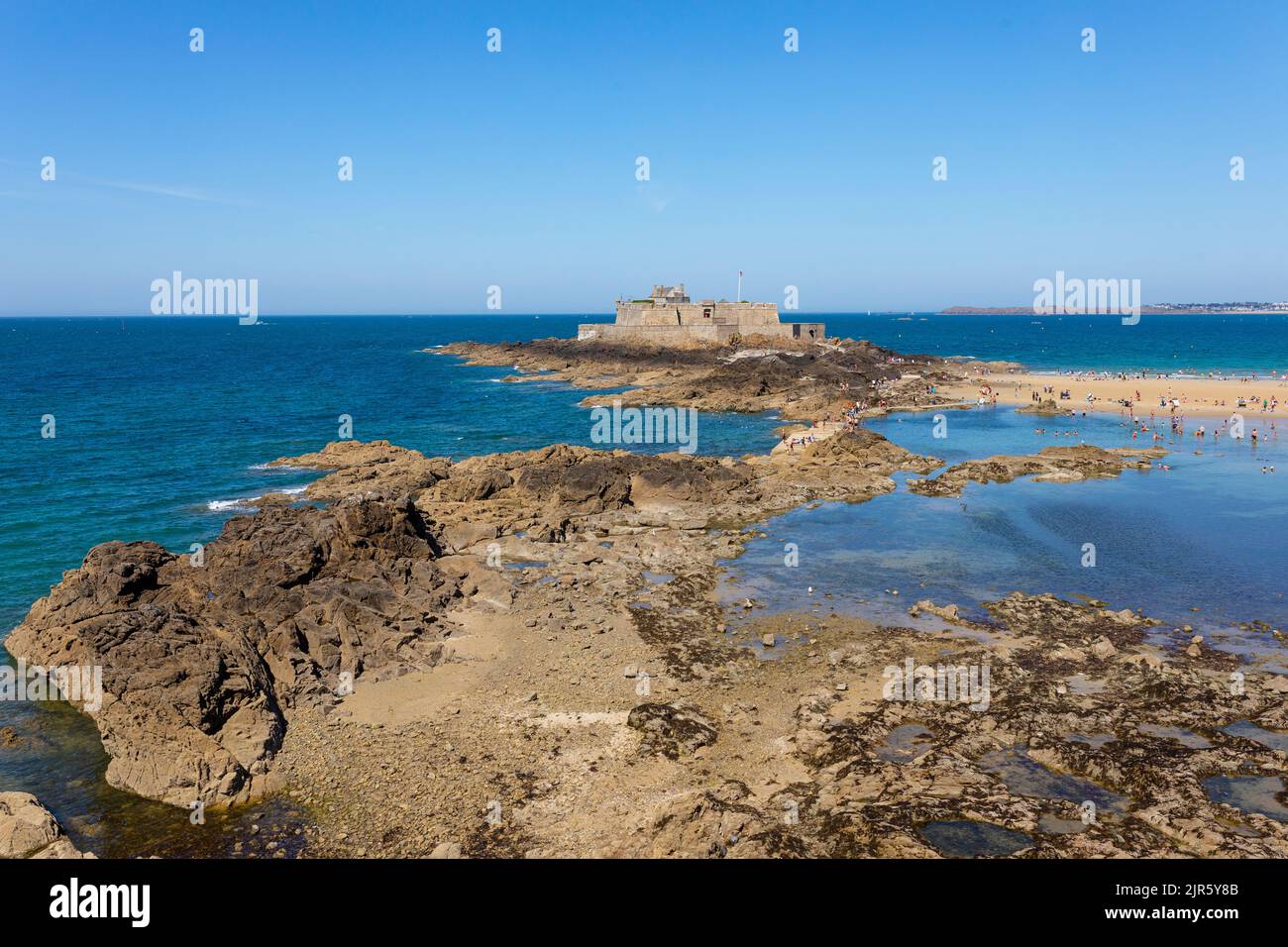Nuoto e prendere il sole persone alla spiaggia di Saint Malo, fortezza sullo sfondo, Bretagna, Francia Foto Stock