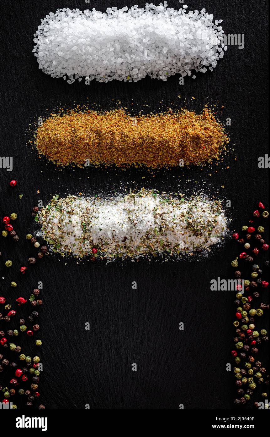 Assortimento di spezie macinate su fondo di pietra scura con spazio copia. Sale Svanstka, erbe provenzali, pepe e mescolare. Foto Stock