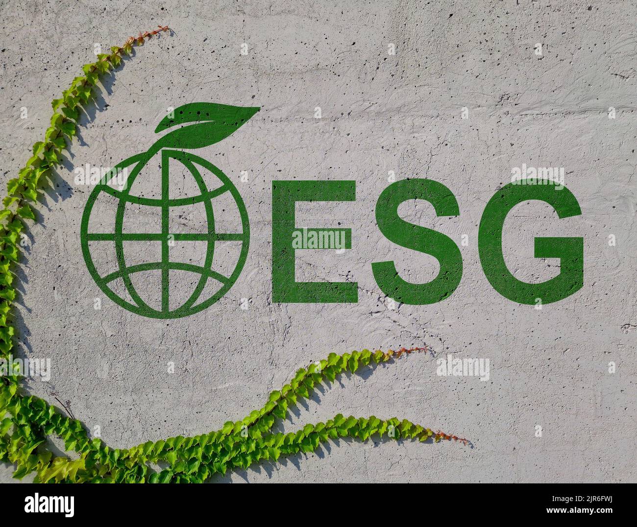 Muro con iscrizione ESG Environmental, Social, and Governance e un globo e foglie verdi. Foto Stock