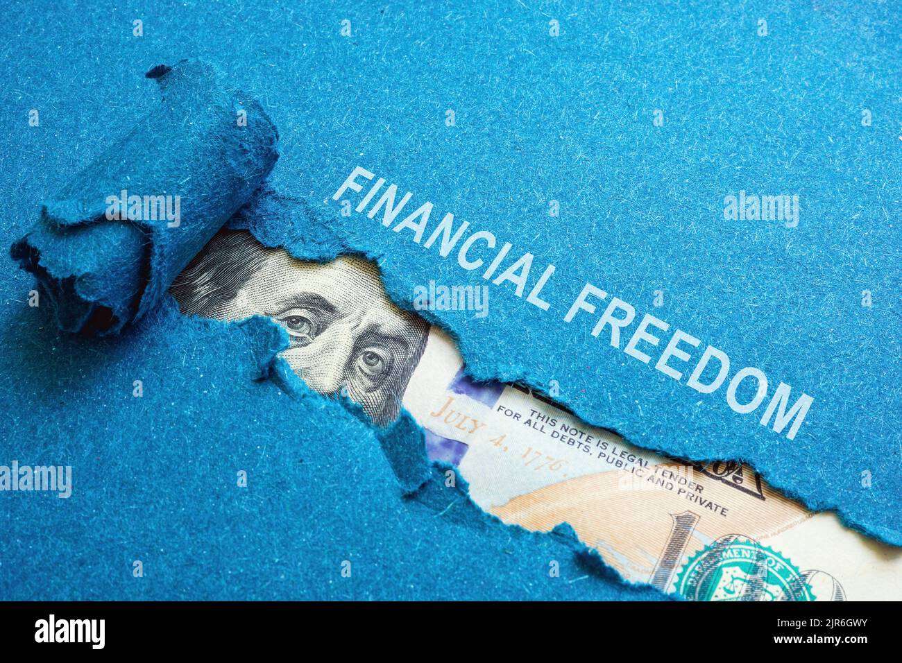 La libertà finanziaria iscrizione su carta strappata e dollari sotto di essa. Foto Stock