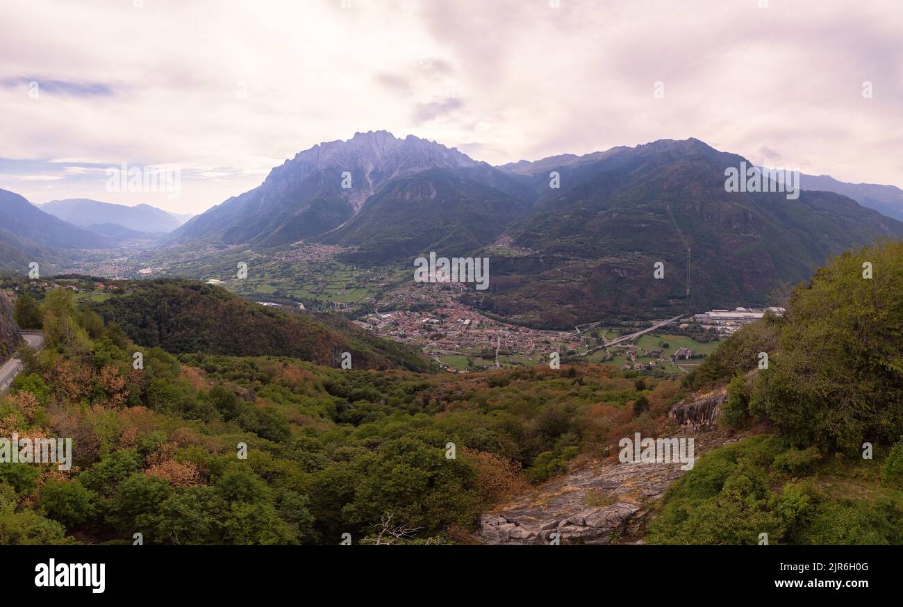 Vista aerea - Una bella vista sul paese in valle tra le montagne - Lombardia, Italia Foto Stock