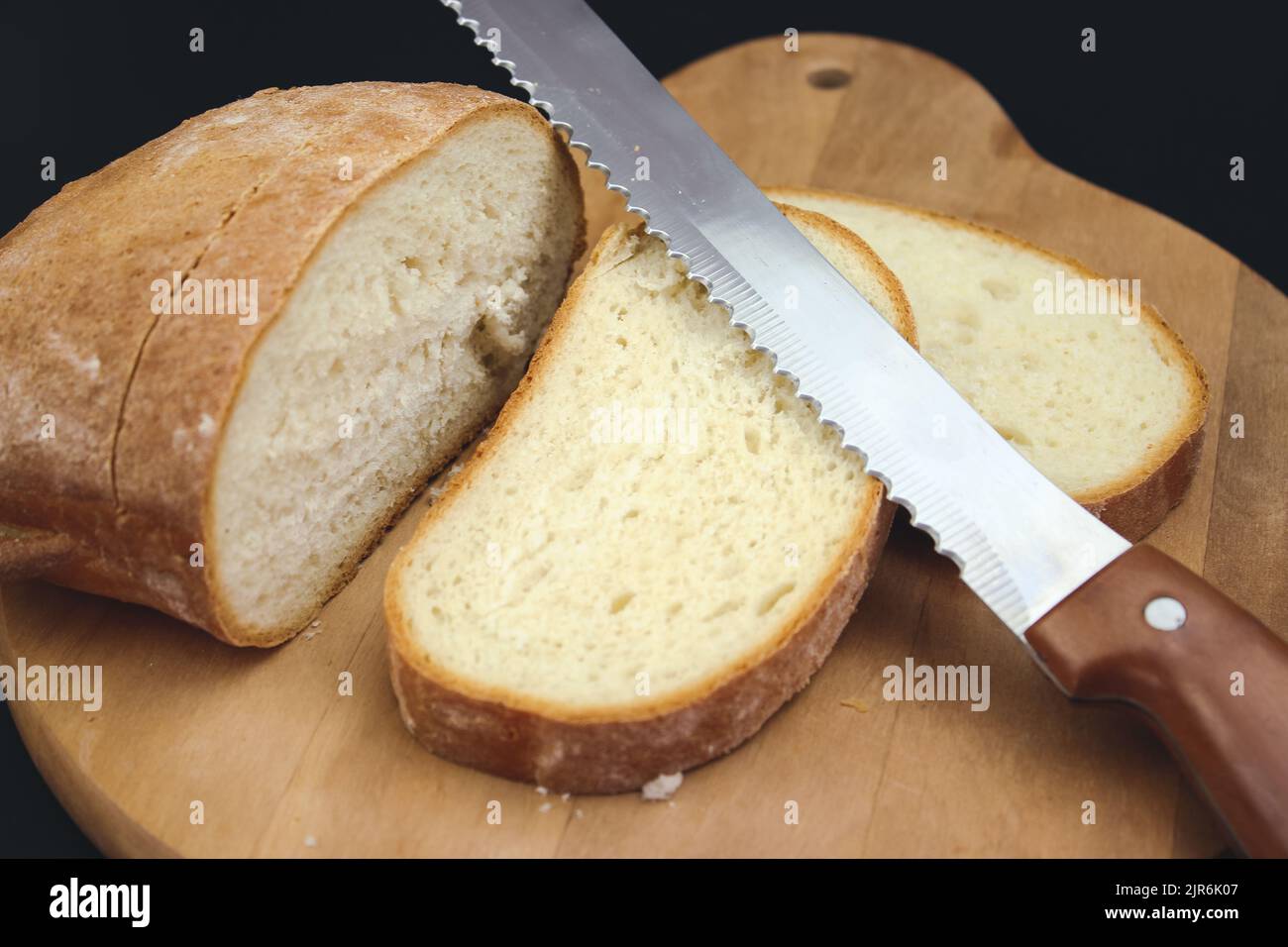 Coltello per pane affettare una pagnotta. Tagliare il pane fresco con un coltello Foto Stock