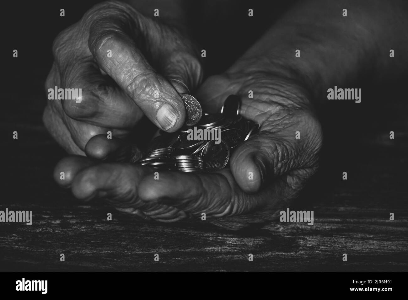 mani di una vecchia donna con penny sul tavolo, soldi nelle mani di un pensionato Foto Stock