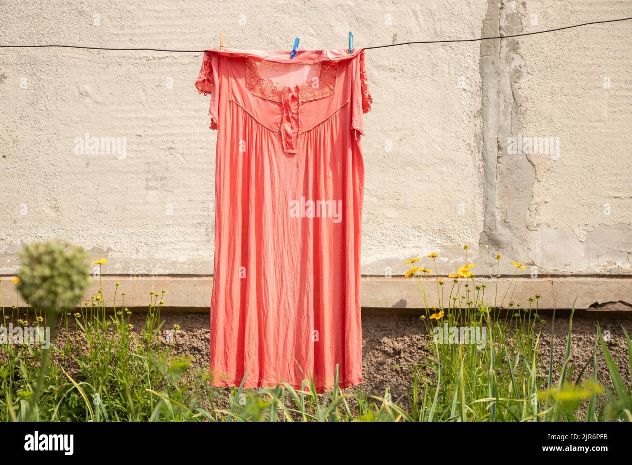 l'abito femminile appende su una corda sulla strada nel cortile vicino alla casa asciuga al sole, vestiti lavati su una corda Foto Stock