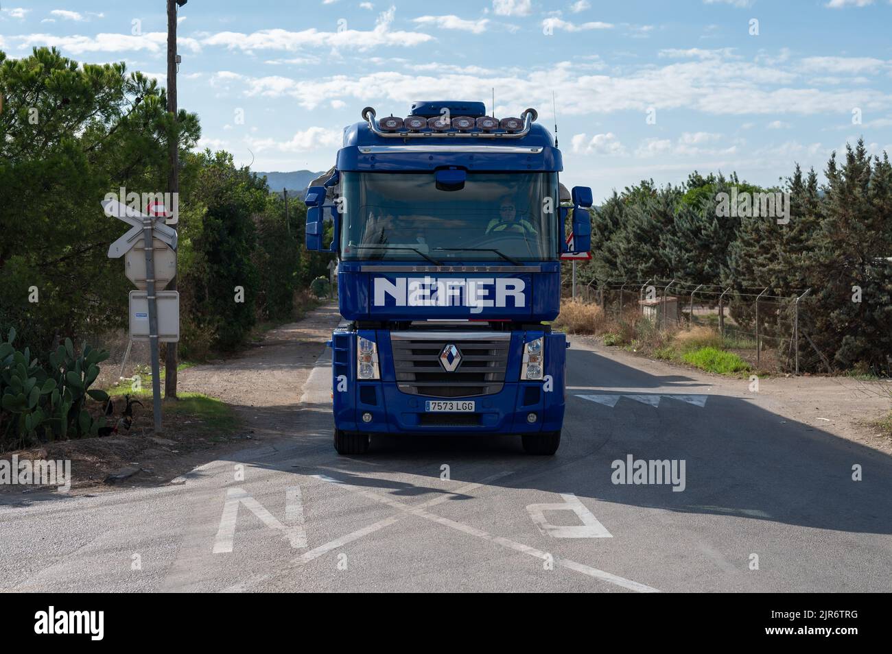 Un grande camion blu Renault Magnum con un rimorchio che lascia la città rurale in condizioni di sole Foto Stock
