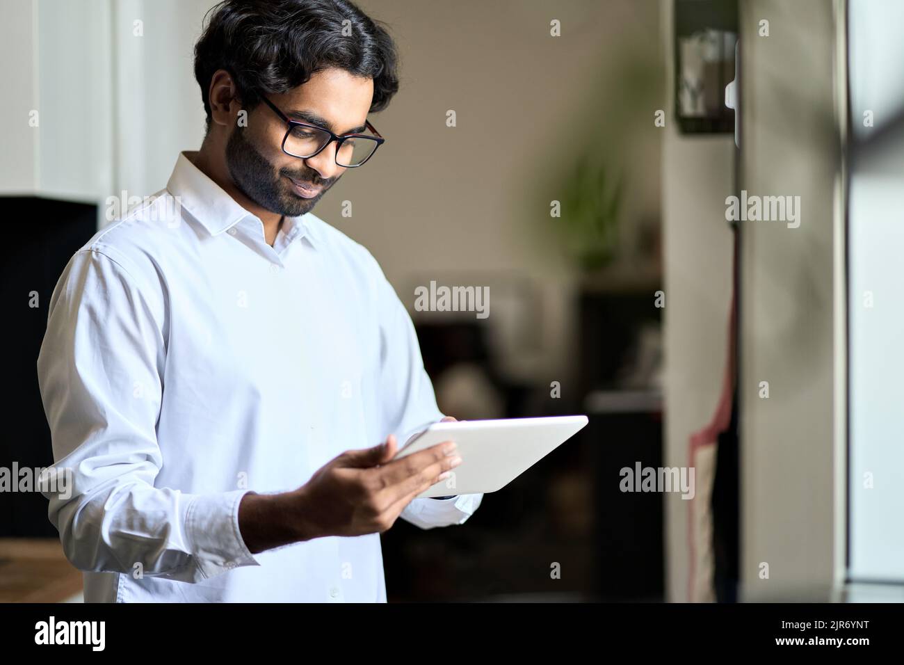 Giovane uomo d'affari indiano sorridente che utilizza un tablet digitale. Foto Stock