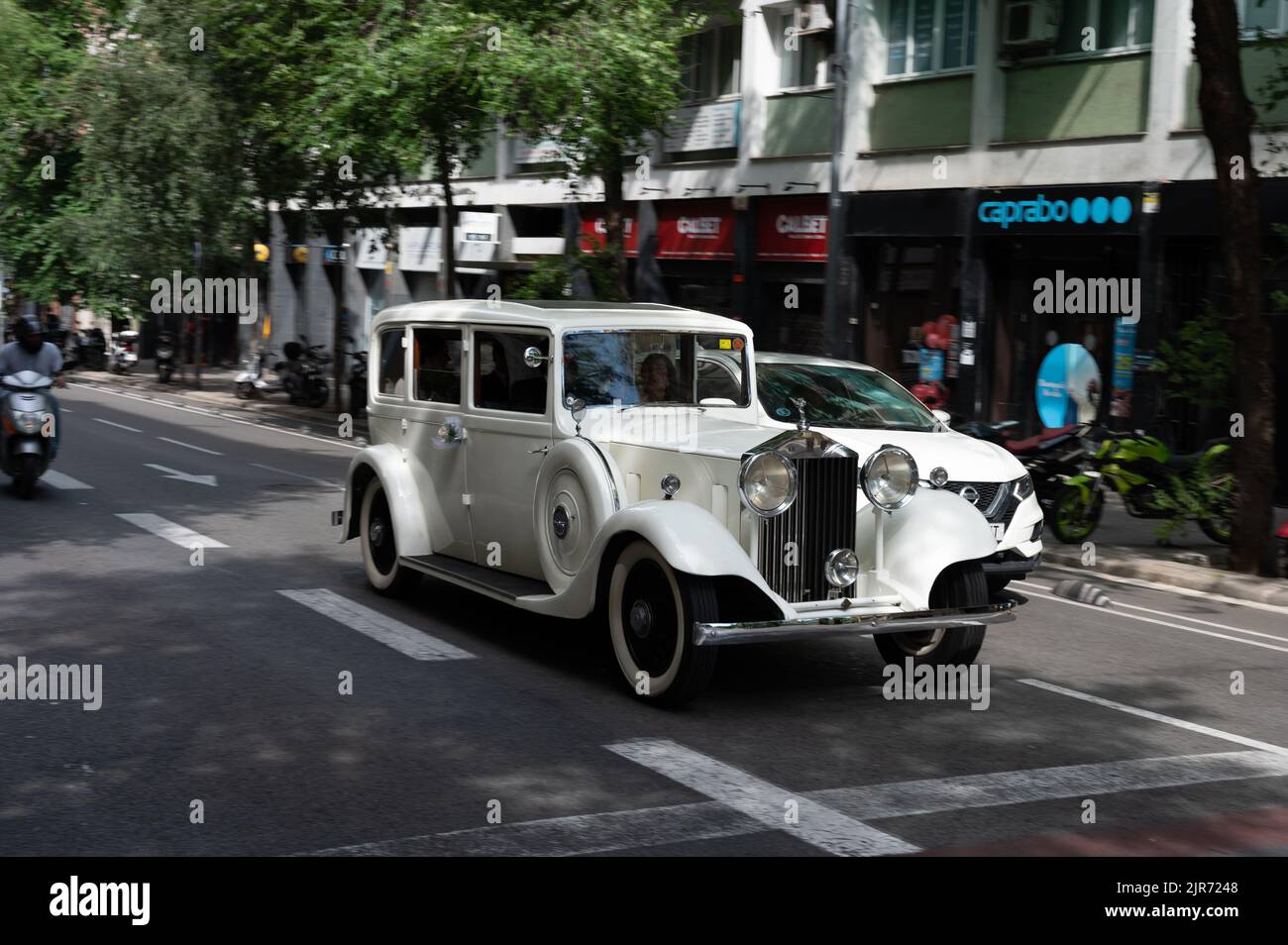 Un vecchio bianco Rolls Royce attraverso le strade della città alla luce del sole Foto Stock