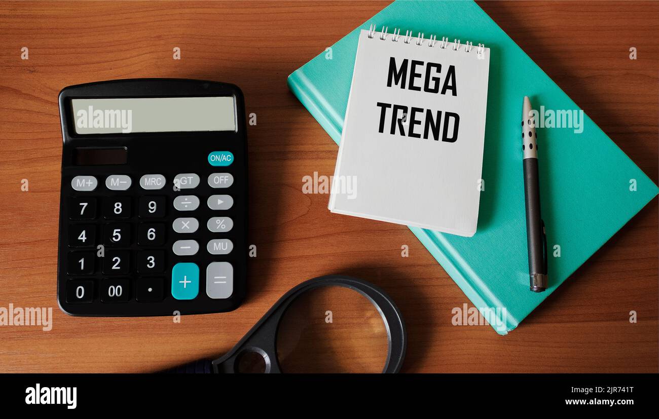 MEGA TREND, testo scritto in un blocco note su un tavolo di legno con calcolatrice, penna, lente di ingrandimento e diario Foto Stock