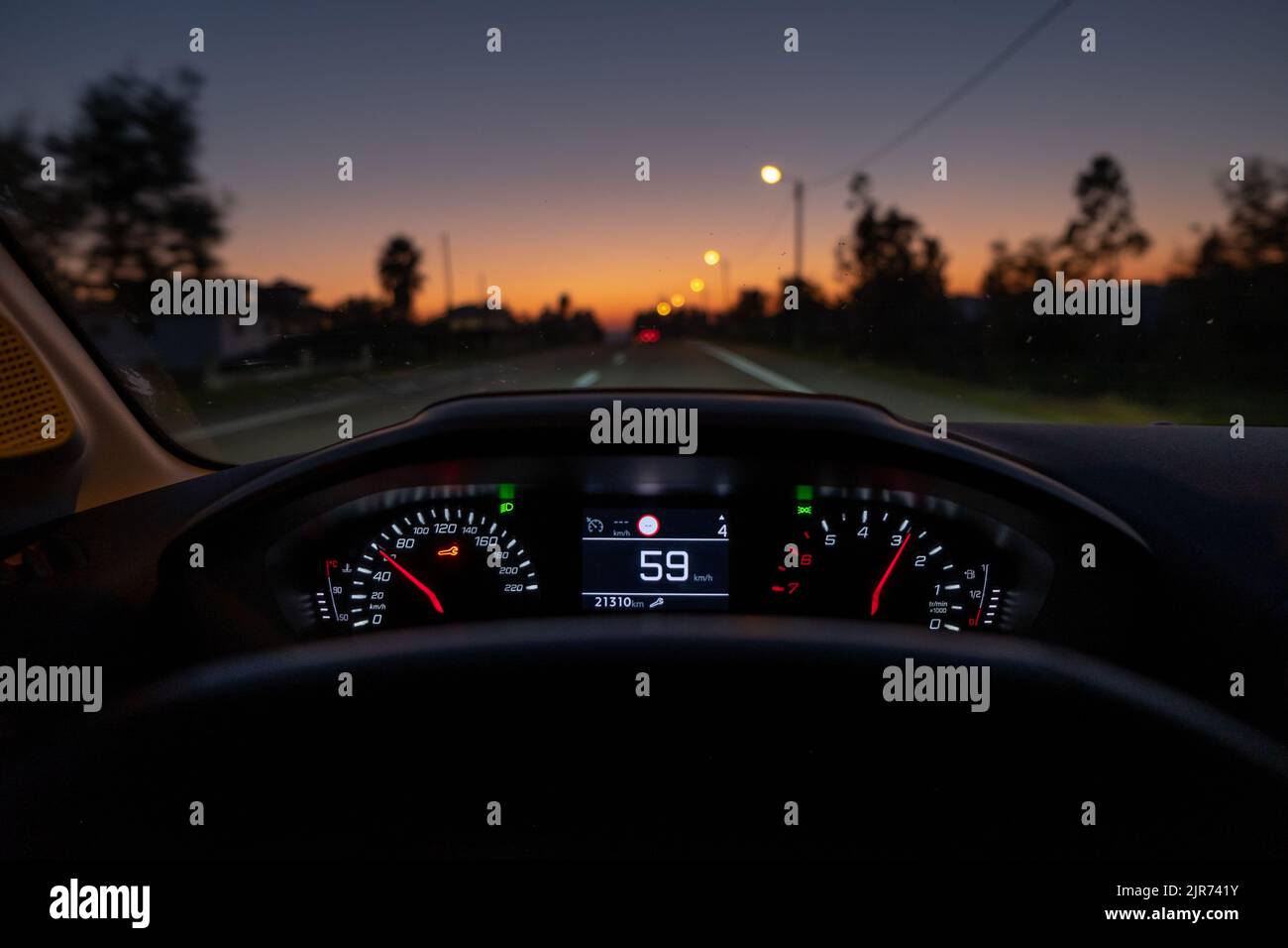 Vista del conducente sul tachimetro a 59 km/h o 59 mph, su una strada sfocata in movimento, vista notturna dall'interno di un'auto del conducente POV del paesaggio stradale Foto Stock