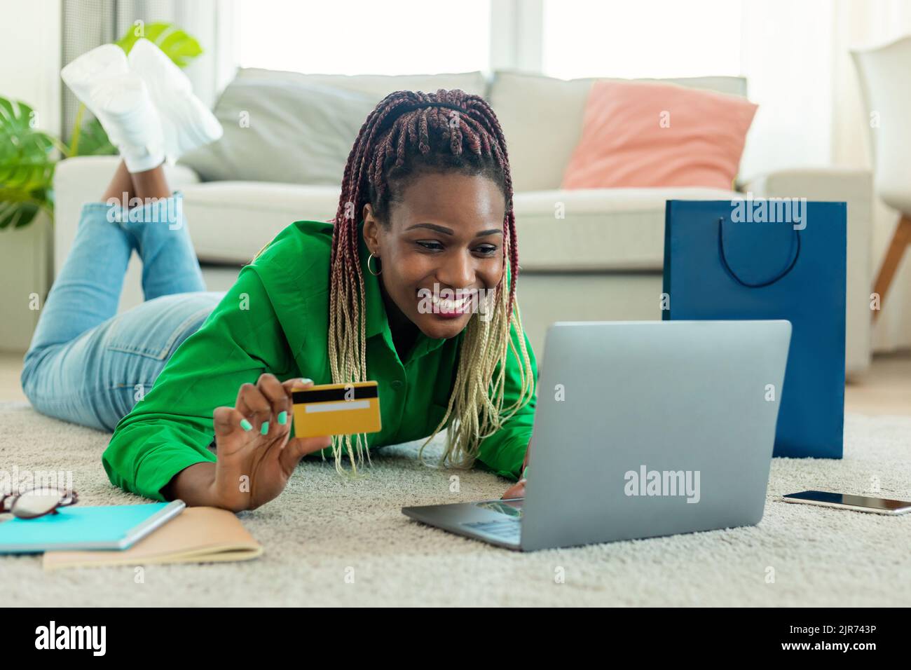 È il momento di fare shopping. Donna afro-americana felice che usa il laptop e che tiene la carta di credito, facendo gli acquisti Foto Stock