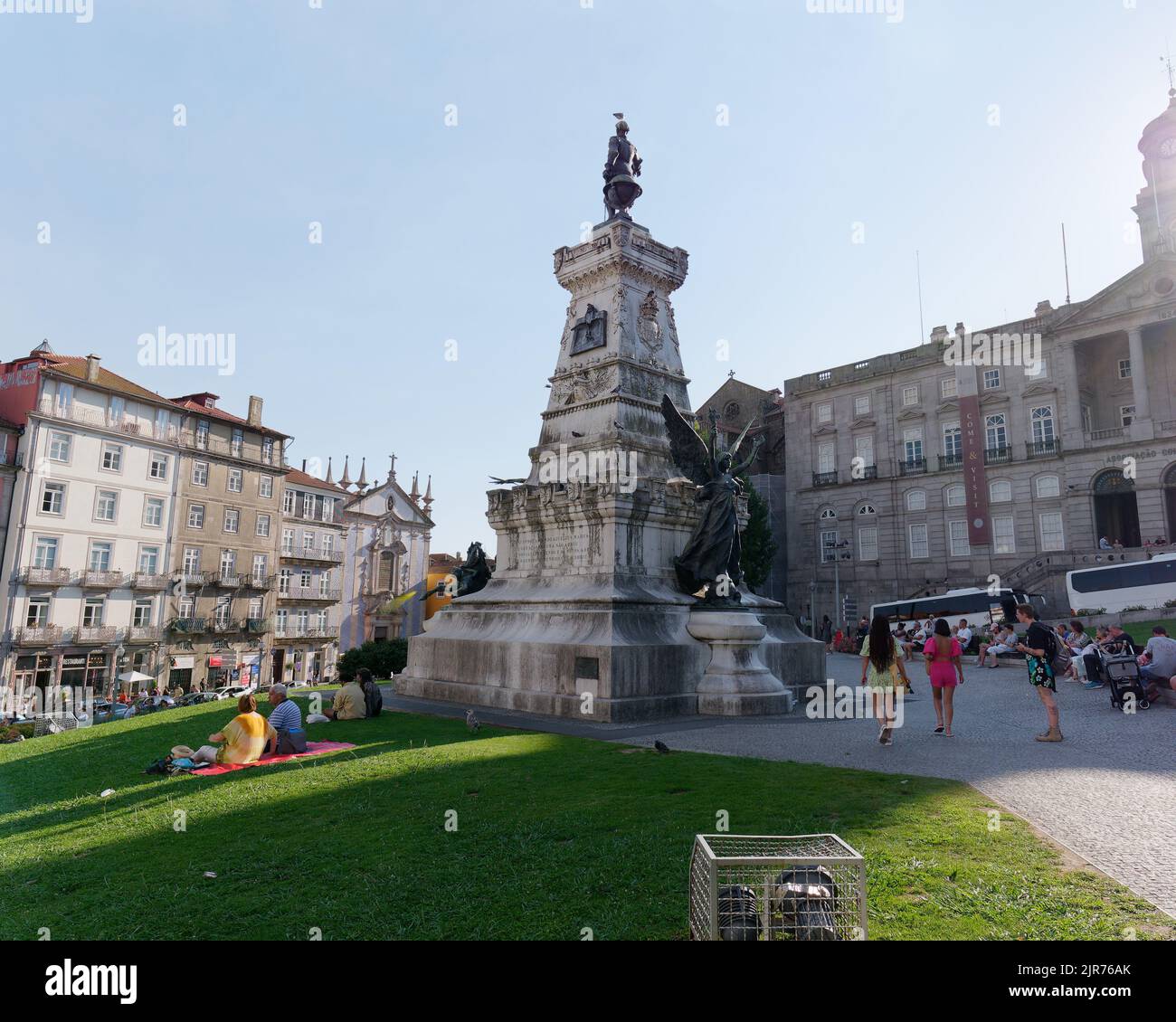 Statua del Principe Enrico il navigatore fuori dal Palazzo Bolsa a Porto Portogallo in una giornata estiva mentre la gente siede sul prato. Foto Stock