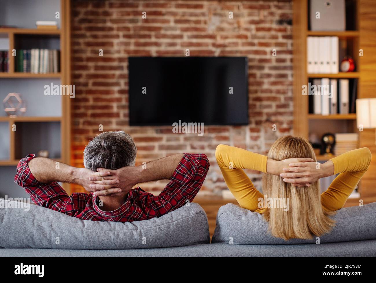 Sorridente marito e moglie caucasica di mezza età si rilassano, guardano la tv con schermo vuoto e si godono del tempo libero Foto Stock