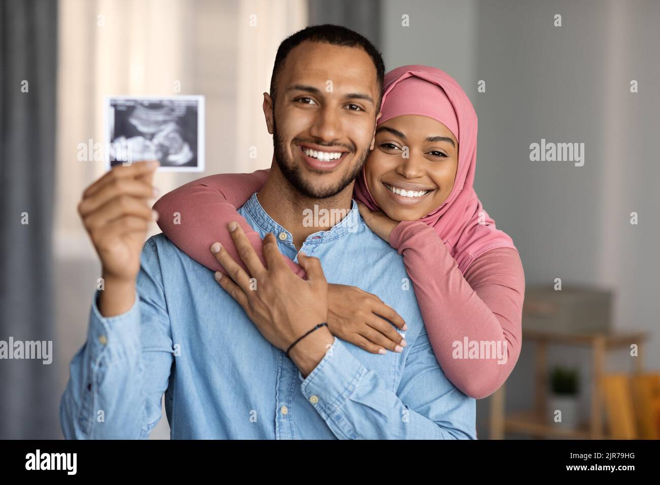 Concetto di parto. Felice coppia musulmana nera che aspetta il bambino, mostrando la sonografia alla macchina fotografica Foto Stock