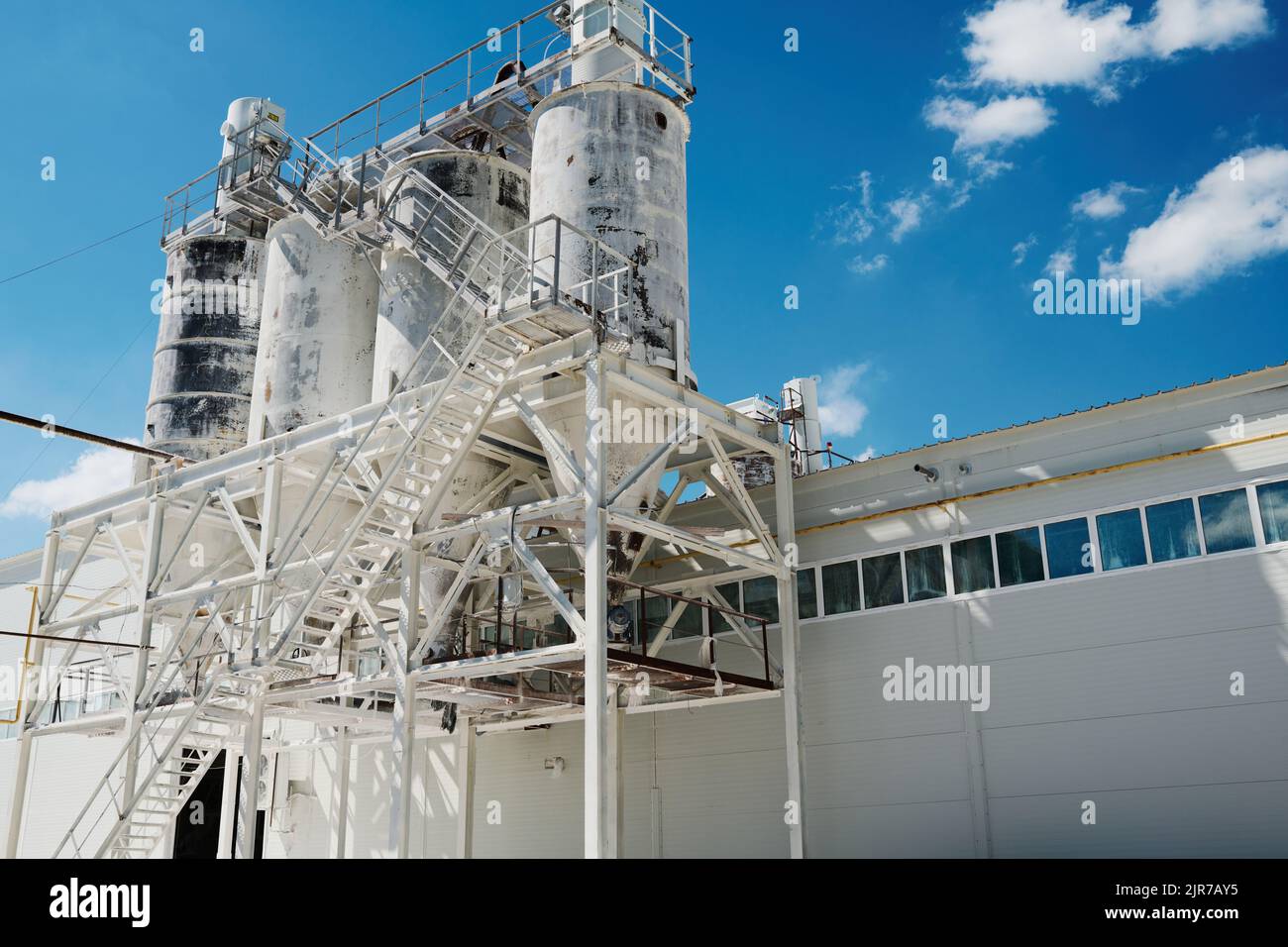 Enorme struttura metallica dipinta di bianco che è la costruzione di una fabbrica moderna o di impianti industriali che producono macchine o qualche altro materiale Foto Stock