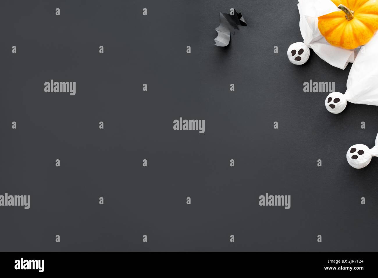 Tre fantasmi bianchi, zucca, pipistrello e parola Halloween su sfondo nero, concetto di Halloween. Cartolina, spazio di copia Foto Stock