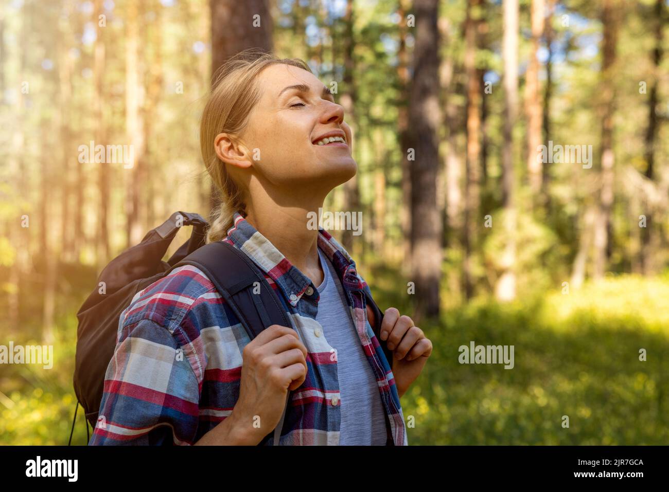 donna zaino in spalla godere della natura nella foresta con gli occhi chiusi. all'aperto rilassante. stress sollievo, salute mentale Foto Stock