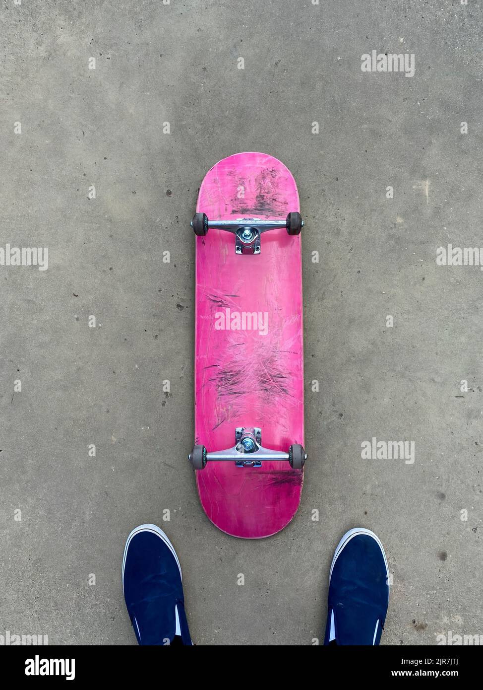 Scricchiolò su skateboard rosa che si posa su una superficie liscia in cemento presso lo skatepark locale Foto Stock