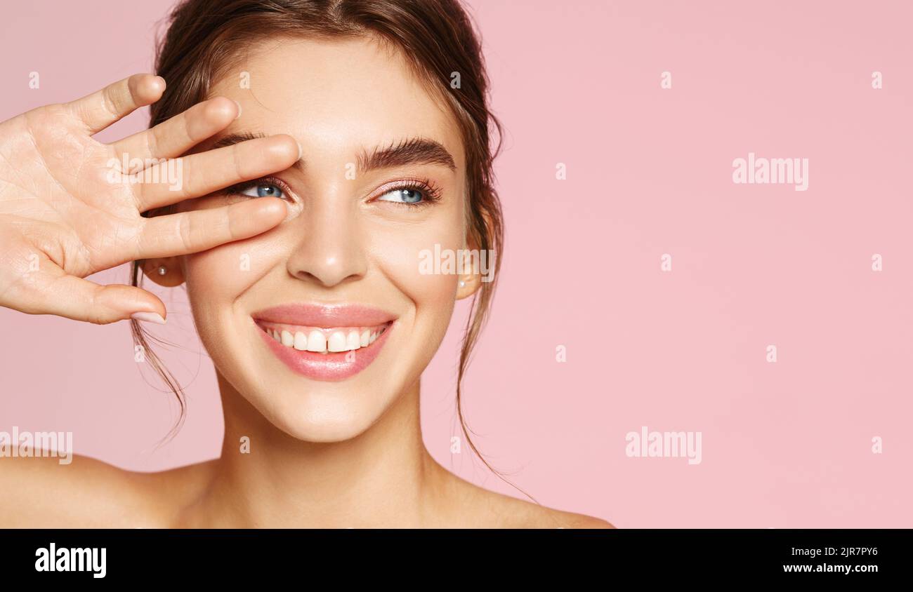 Cura della pelle. Donna con bellezza viso che tocca sano ritratto della pelle del viso. Bella modella sorridente ragazza con trucco naturale che tocca incandescente idratato Foto Stock