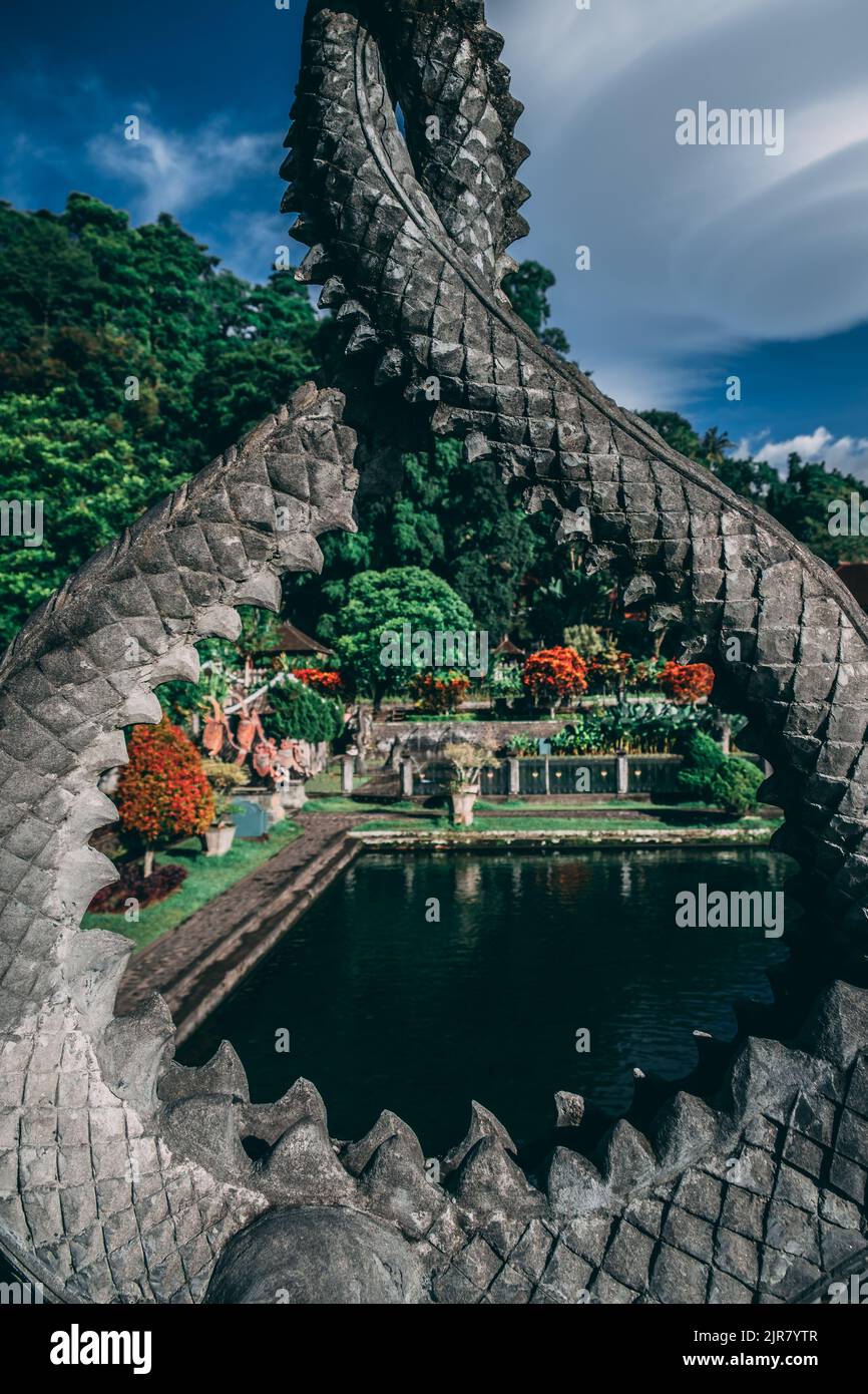 Uno scatto verticale attraverso una caratteristica di pietra di un lago circondato da piante e alberi a Bali Foto Stock